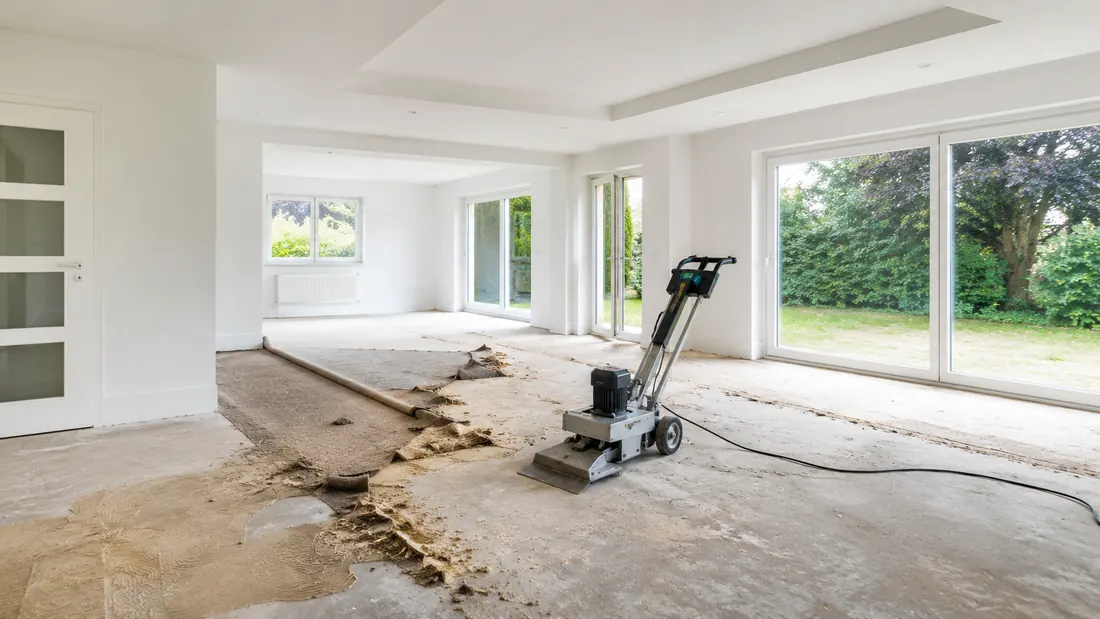 Teppichentfernung in einem hellen Wohnraum mit Bodenschleifmaschine und vorbereitetem Untergrund
