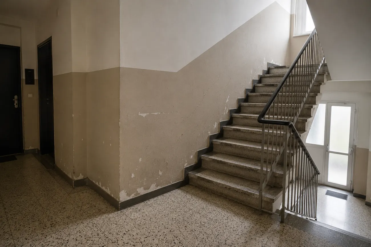 Treppenhaus vor der Aufwertung mit abgenutzten Wandflächen und renovierungsbedürftigem Eingangsbereich