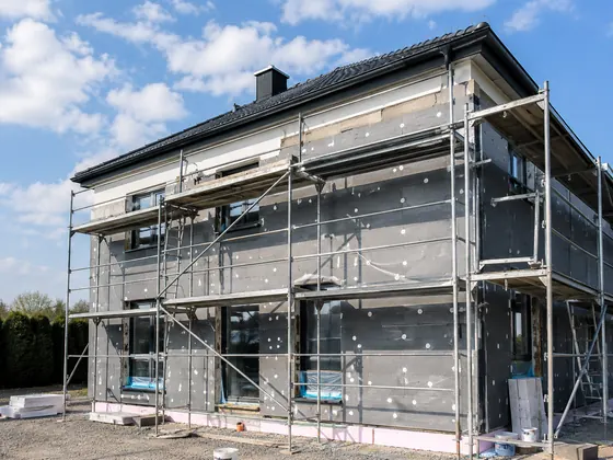 Fassadendämmung an einem eingerüsteten Haus mit grauen Dämmplatten