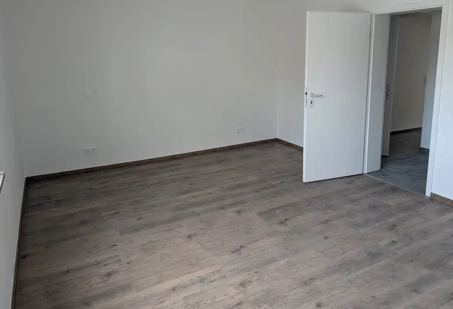 Neu verlegter Laminatboden in einem hellen Wohnraum mit sauber montierten Sockelleisten