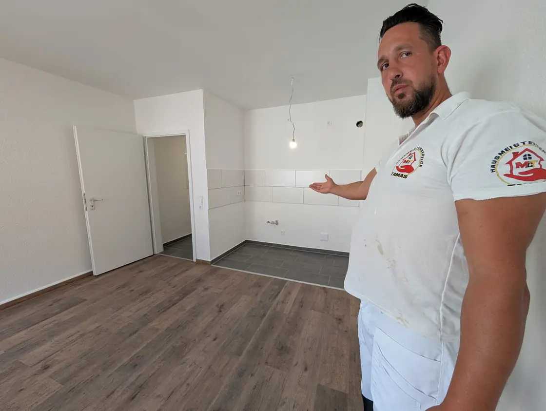 Wohnraum mit neuem Laminatboden und gefliestem Küchenbereich im Übergang.