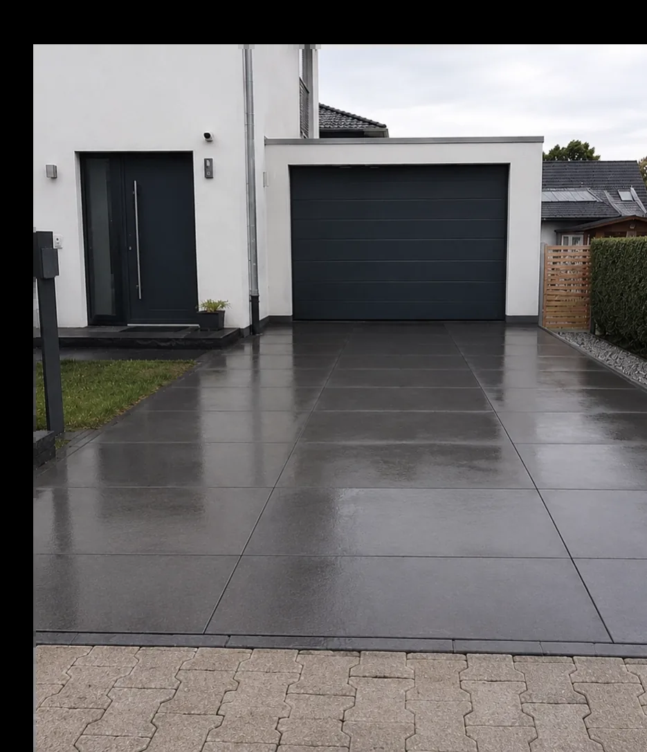 Modern gepflasterte Einfahrt vor einem Einfamilienhaus mit großformatigen Pflastersteinen.