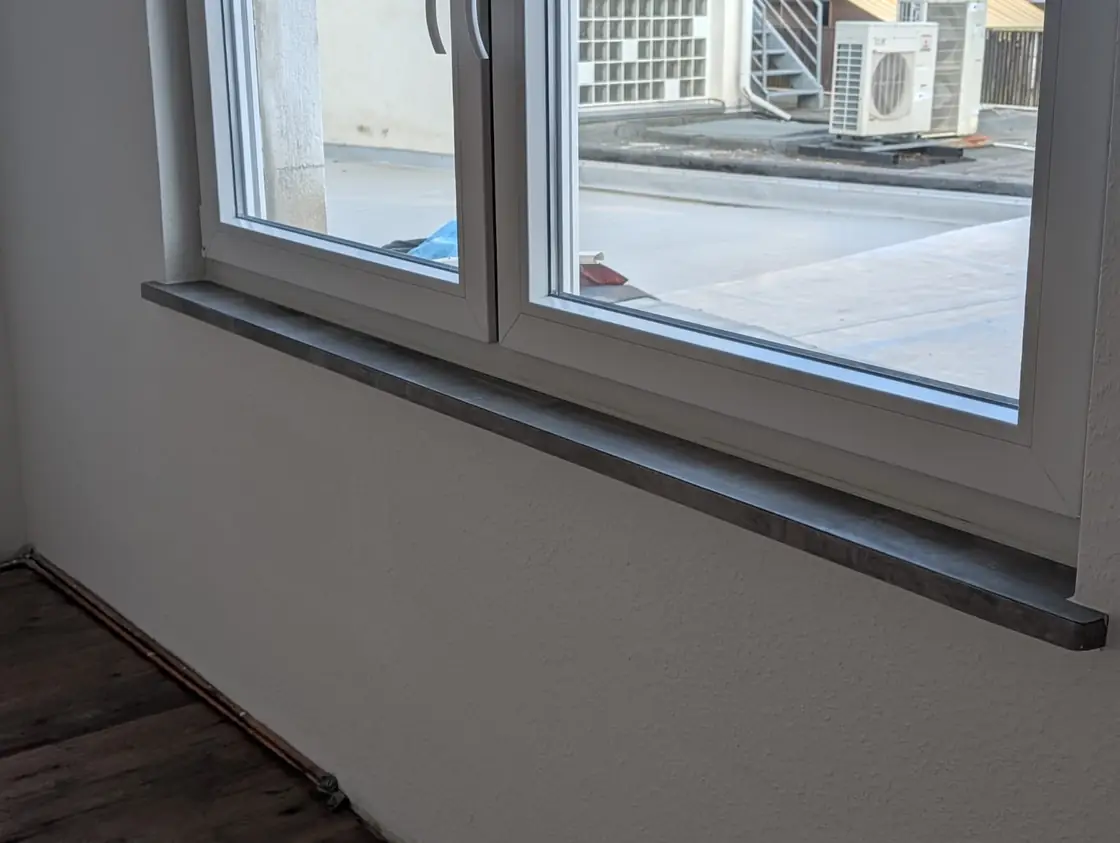 Innenausbau am Fenster mit sauber verkleideter Fensterbank und angrenzendem Bodenbereich.