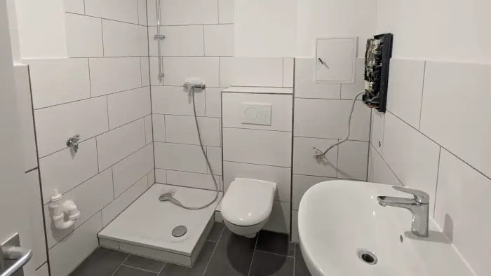Badsanierung und Fliesenarbeiten – hell gefliestes Badezimmer mit Dusche, WC und Waschbecken während der Sanierung