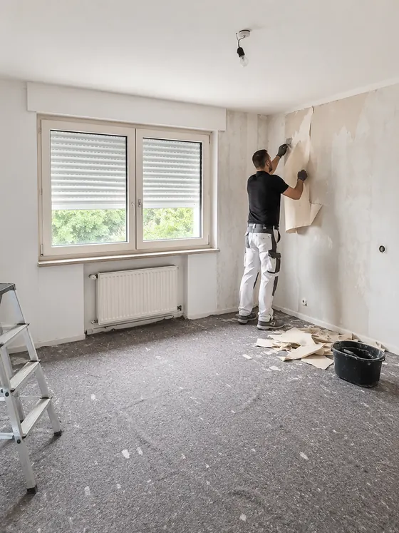 Tapetenentfernung in einem Raum mit vorbereiteten Wandflächen und abgelöster Tapete